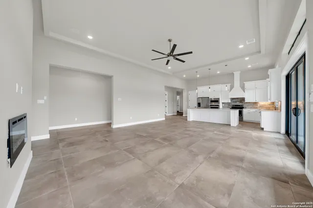 an empty room with wooden floor ceiling fan and windows