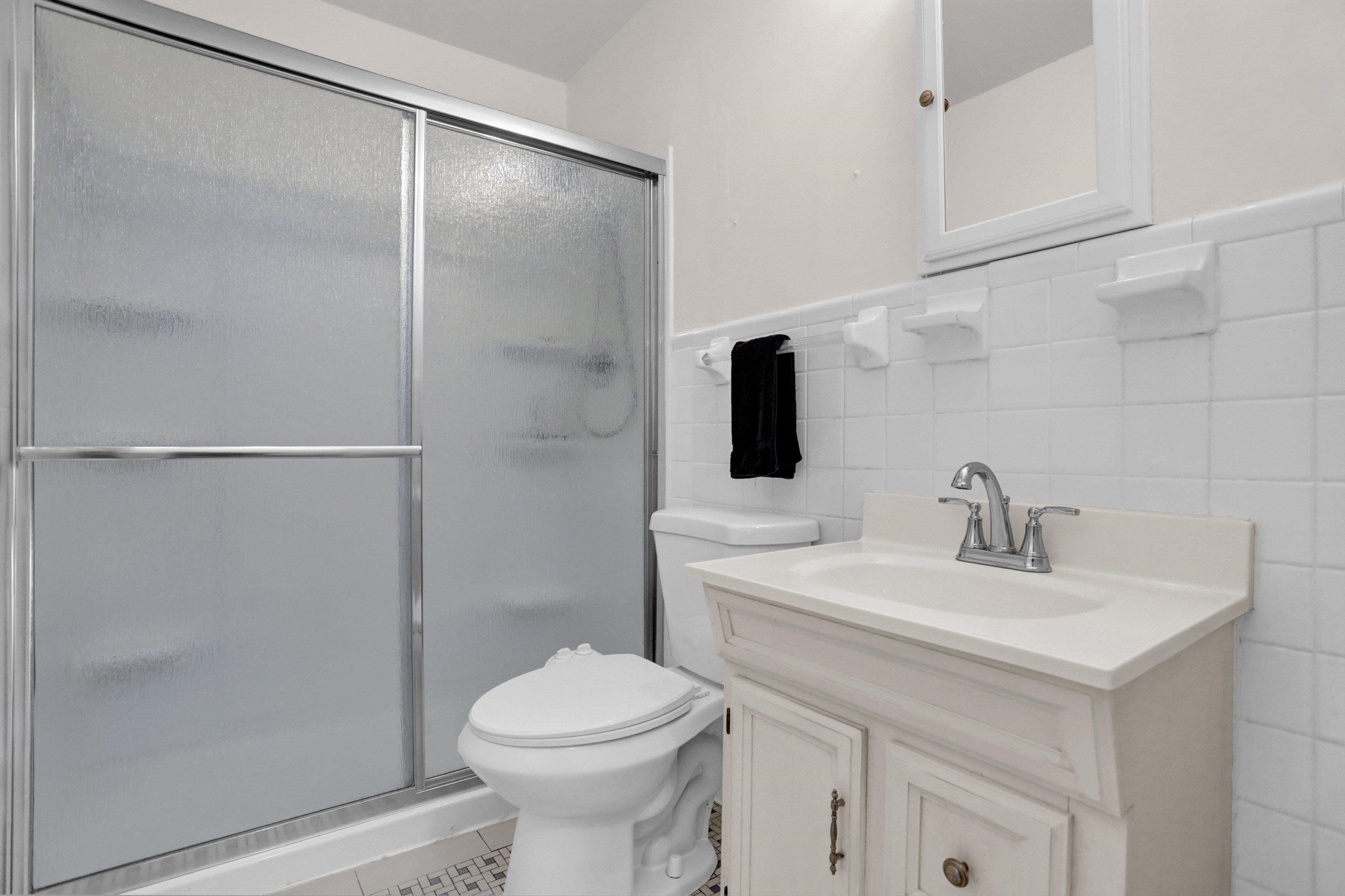 4545 Flamingo Road Memphis, TN 38117 - Photo 18 of 34 Bathroom featuring a glass-enclosed shower with frosted panels, white square wall tiles, a vanity with under-sink cabinetry, a recessed sink, and a mirrored medicine cabinet