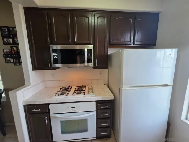a kitchen with granite countertop a refrigerator stove and microwave with wooden floor