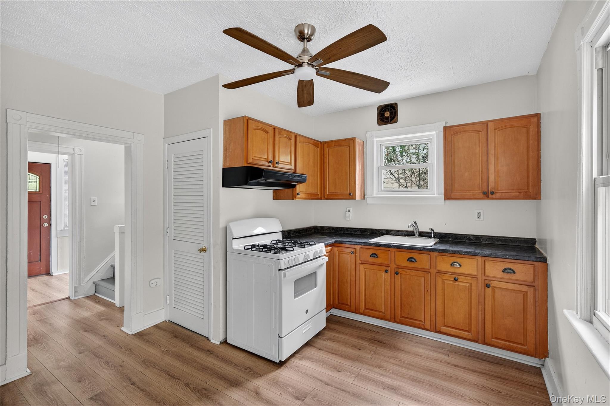72 Smith Clove Road Central Valley, NY 10917 - Photo 14 of 35 Kitchen with white gas range, dark countertops, brown cabinets, light wood-style flooring, and a textured ceiling