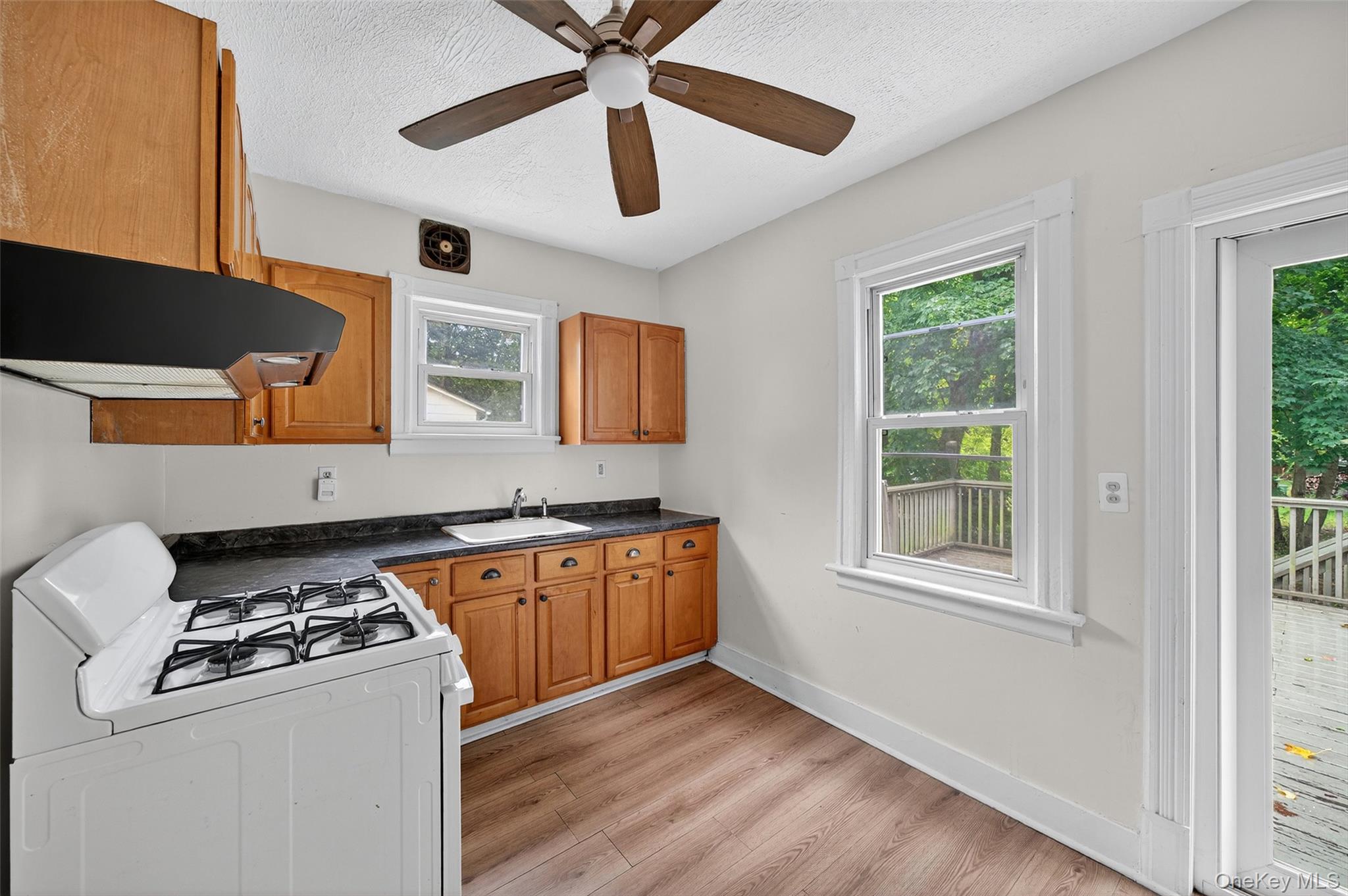 72 Smith Clove Road Central Valley, NY 10917 - Photo 15 of 35 Kitchen with white range with gas cooktop, dark countertops, under cabinet range hood, brown cabinets, and a textured ceiling