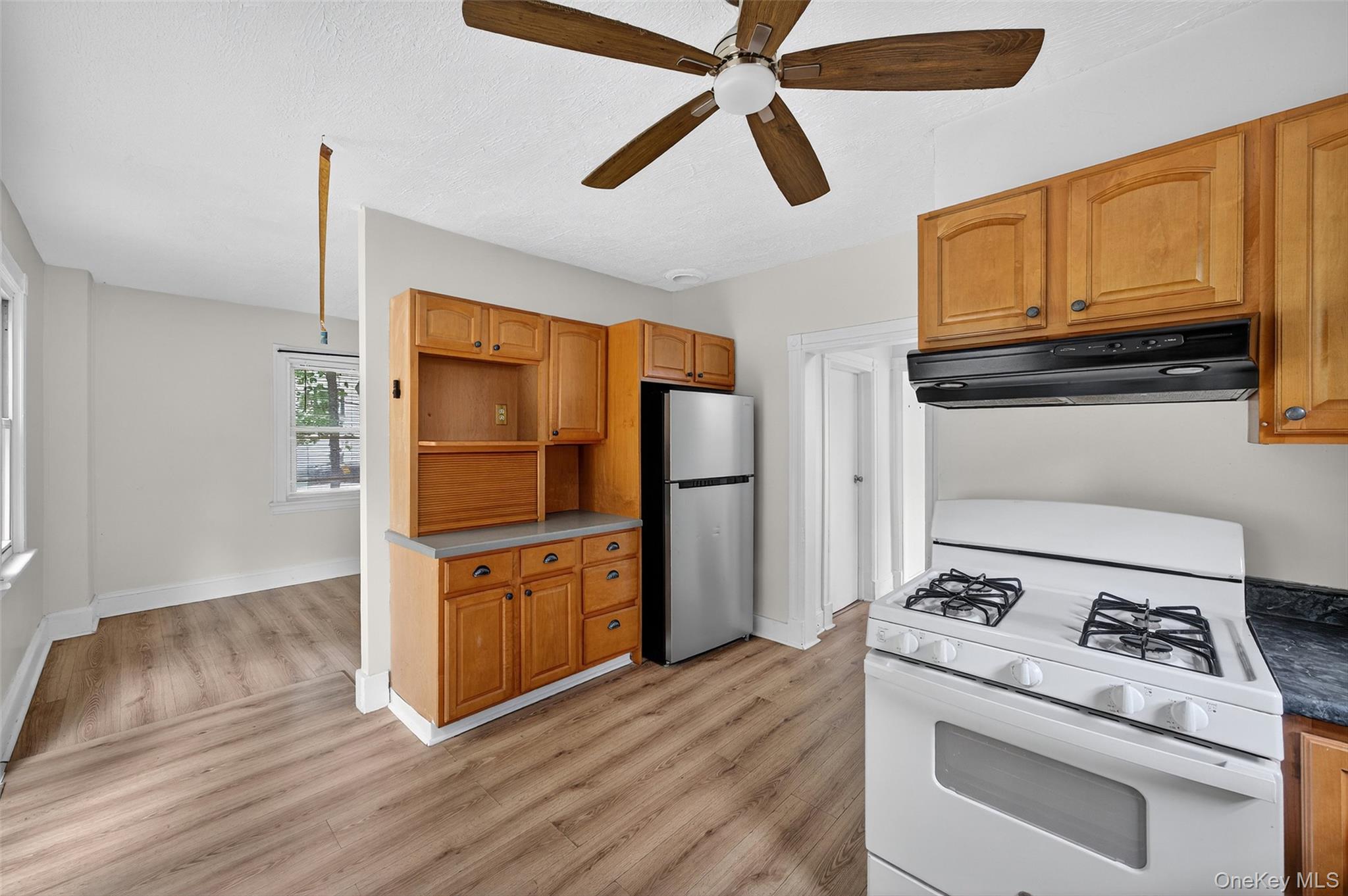 72 Smith Clove Road Central Valley, NY 10917 - Photo 16 of 35 Kitchen with white range with gas stovetop, ventilation hood, freestanding refrigerator, light wood finished floors, and brown cabinets