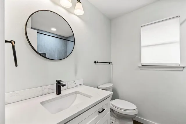 a bathroom with a sink a toilet and a mirror