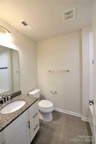 a bathroom with a granite countertop sink a toilet and a mirror