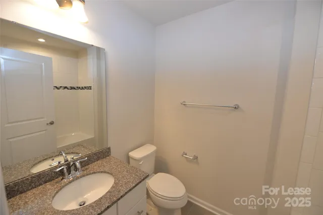 a bathroom with a granite countertop sink toilet a mirror and a shower