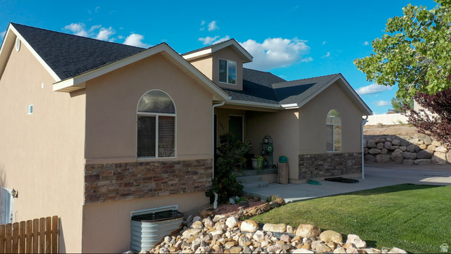 1797 Sunset Road Enoch, UT 84721 - Photo 4 of 80 Stucco exterior featuring a stone veneer accent, arched windows, and a dark shingle roof