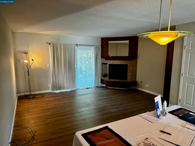 a view of a room with wooden floor kitchen view and a fireplace