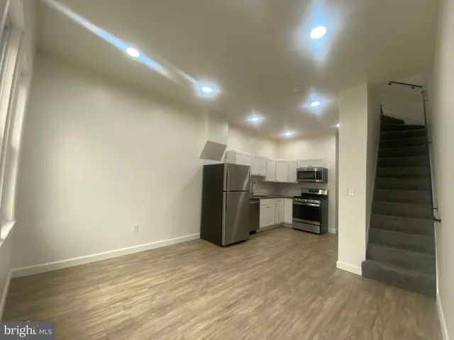 an empty room with kitchen and natural light