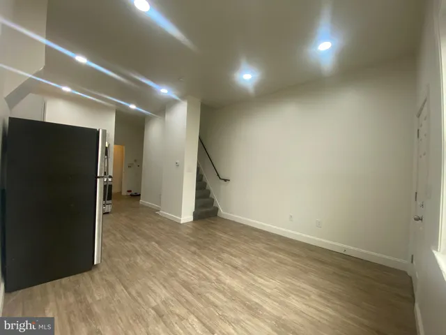 an empty room with wooden floor and a hallway