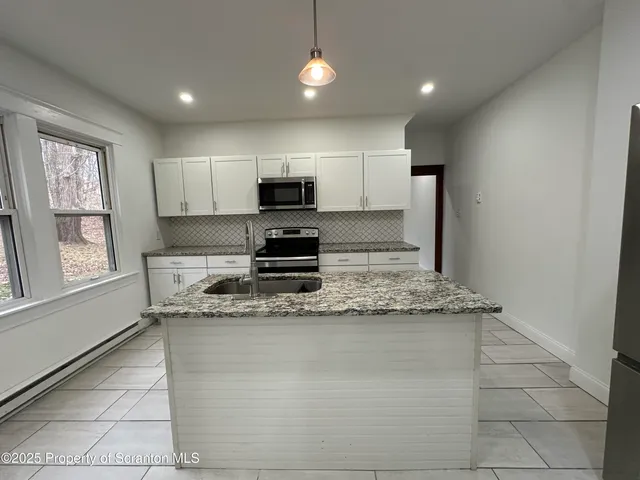 a kitchen with kitchen island granite countertop a sink appliances cabinets and a counter top space