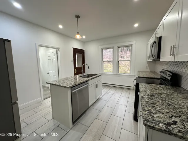 a kitchen with granite countertop a sink and cabinets