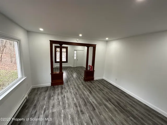 a view of empty room with wooden floor and fan
