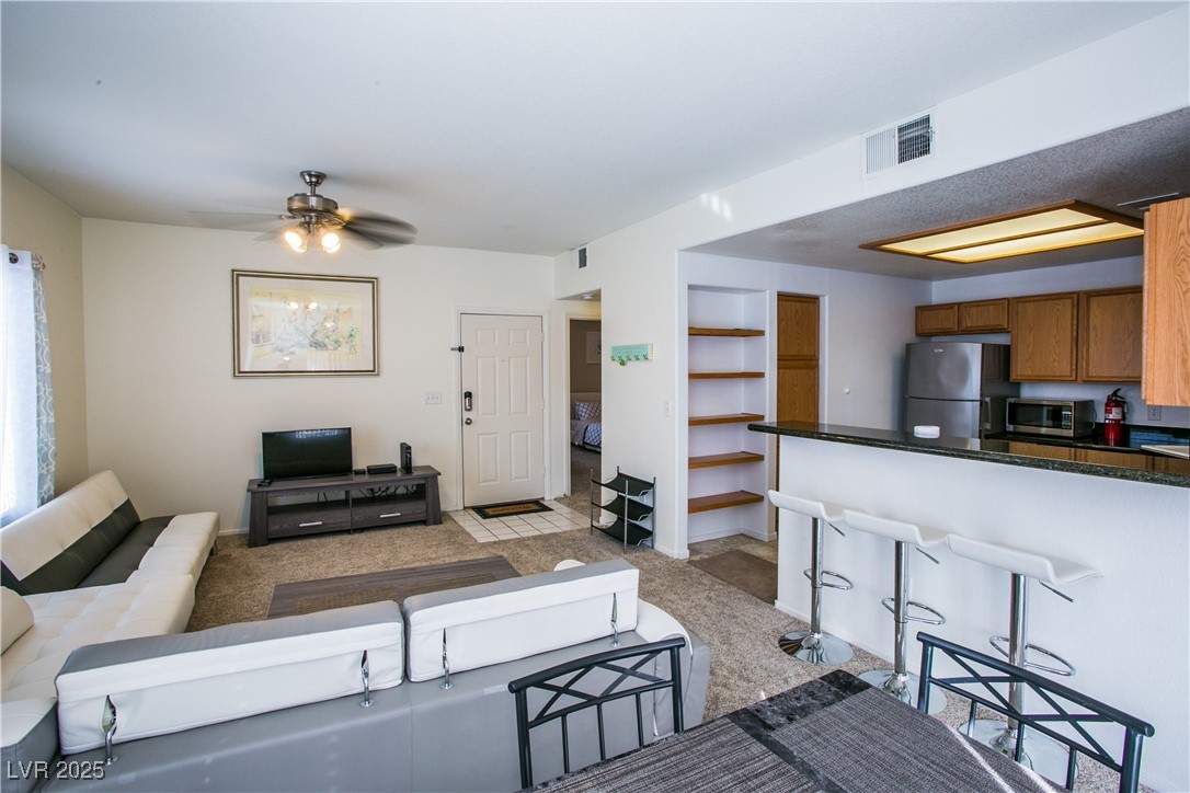 4655 Gold Dust Avenue, Unit 206 Las Vegas, NV 89120 - Photo 13 of 34 Living area featuring light carpet and a ceiling fan