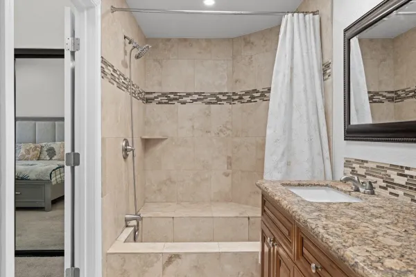 a bathroom with a granite countertop sink a mirror and shower