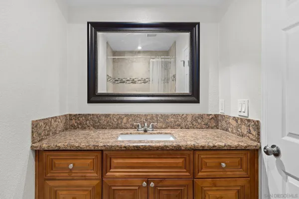 a bathroom with a granite countertop sink and a mirror