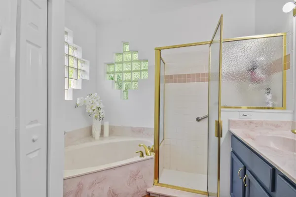 a bathroom with a granite countertop sink a mirror a bathtub and shower