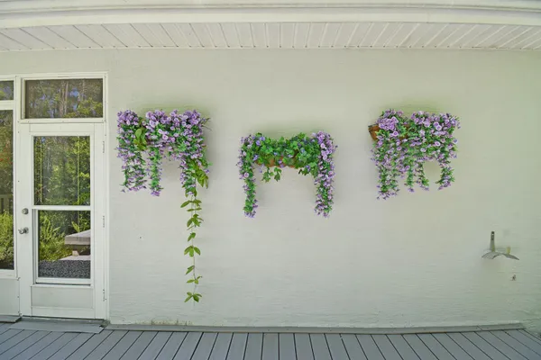 a white wall with a vase of flowers on it