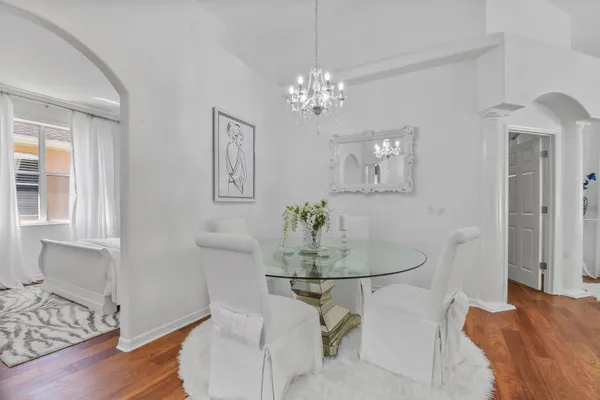 a dining room with chandelier and wooden floor
