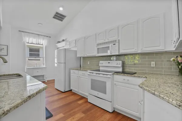 a kitchen with granite countertop white cabinets and white stainless steel appliances