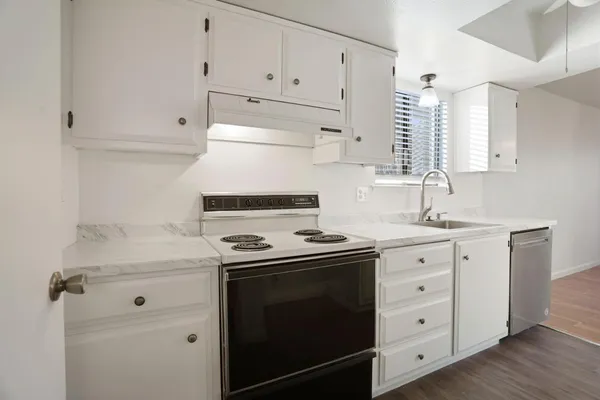 a kitchen with granite countertop white cabinets and white stove