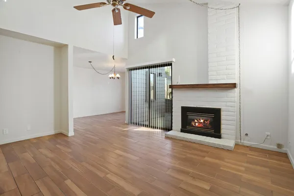 a view of an empty room with wooden floor fireplace and a window