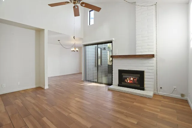 a view of an empty room with wooden floor fireplace and a window