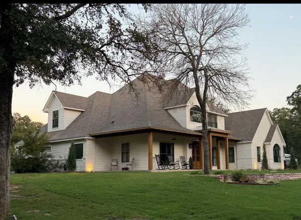 a front view of a house with a garden and trees