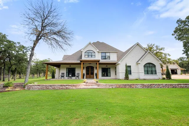 a front view of a house with a garden and trees