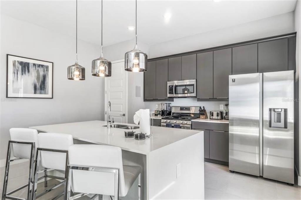 7760 Sandy Ridge Drive, Unit 108 Reunion, FL 34747 - Photo 6 of 16 a kitchen with stainless steel appliances granite countertop a sink a stove a refrigerator cabinets and chairs