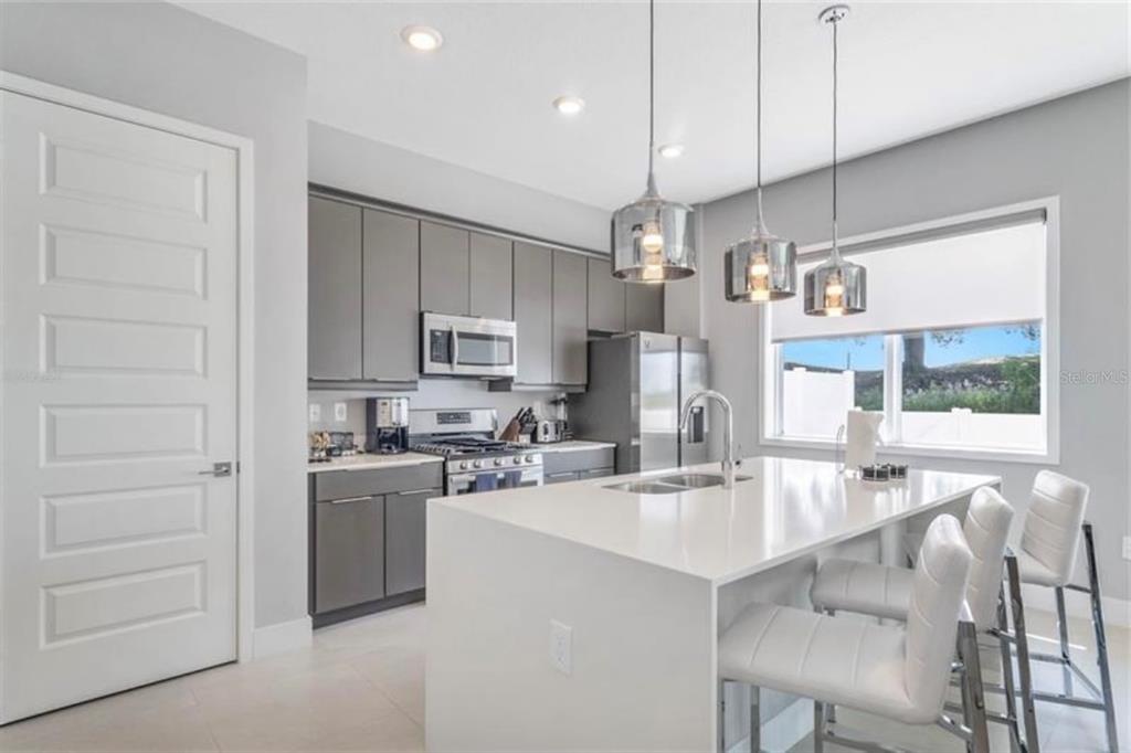7760 Sandy Ridge Drive, Unit 108 Reunion, FL 34747 - Photo 7 of 16 a kitchen with stainless steel appliances kitchen island granite countertop a sink and cabinets