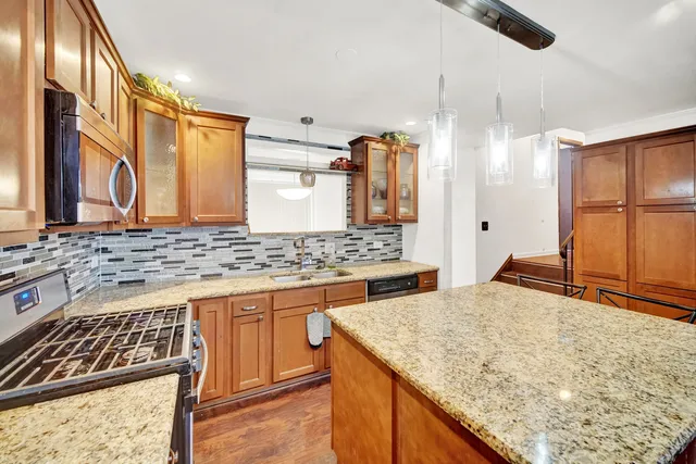 a kitchen with stainless steel appliances granite countertop a sink and a stove