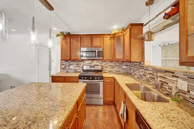 a kitchen with stainless steel appliances granite countertop a stove a sink and a refrigerator