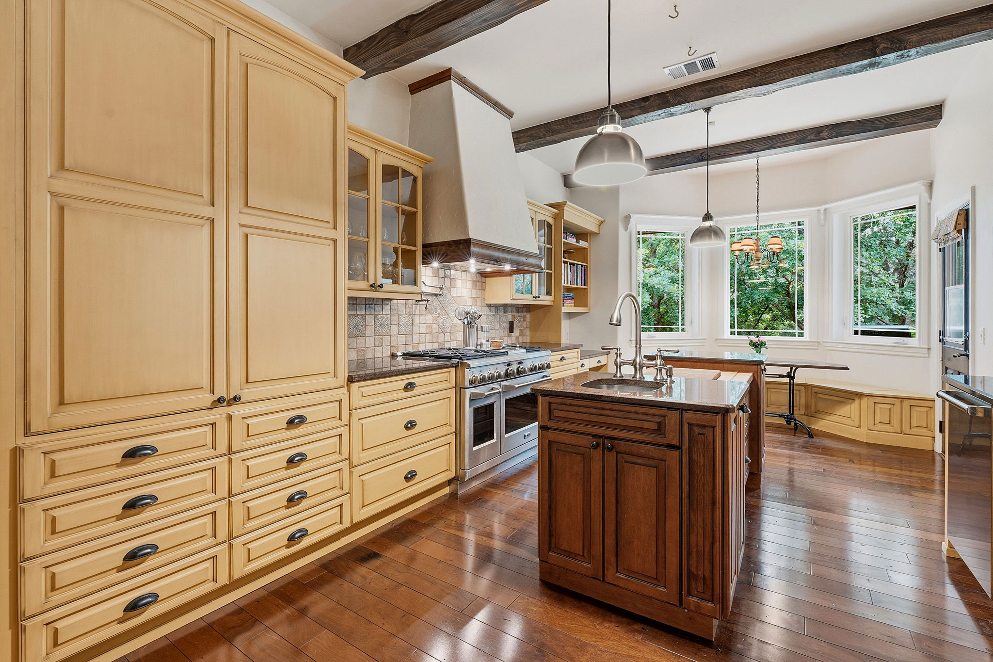 8121 Bluff Trail Austin, TX 78737 - Photo 7 of 40 Rich hardwood floors complement rustic exposed beams in this gourmet kitchen, a perfect blend of warmth and modern amenities.