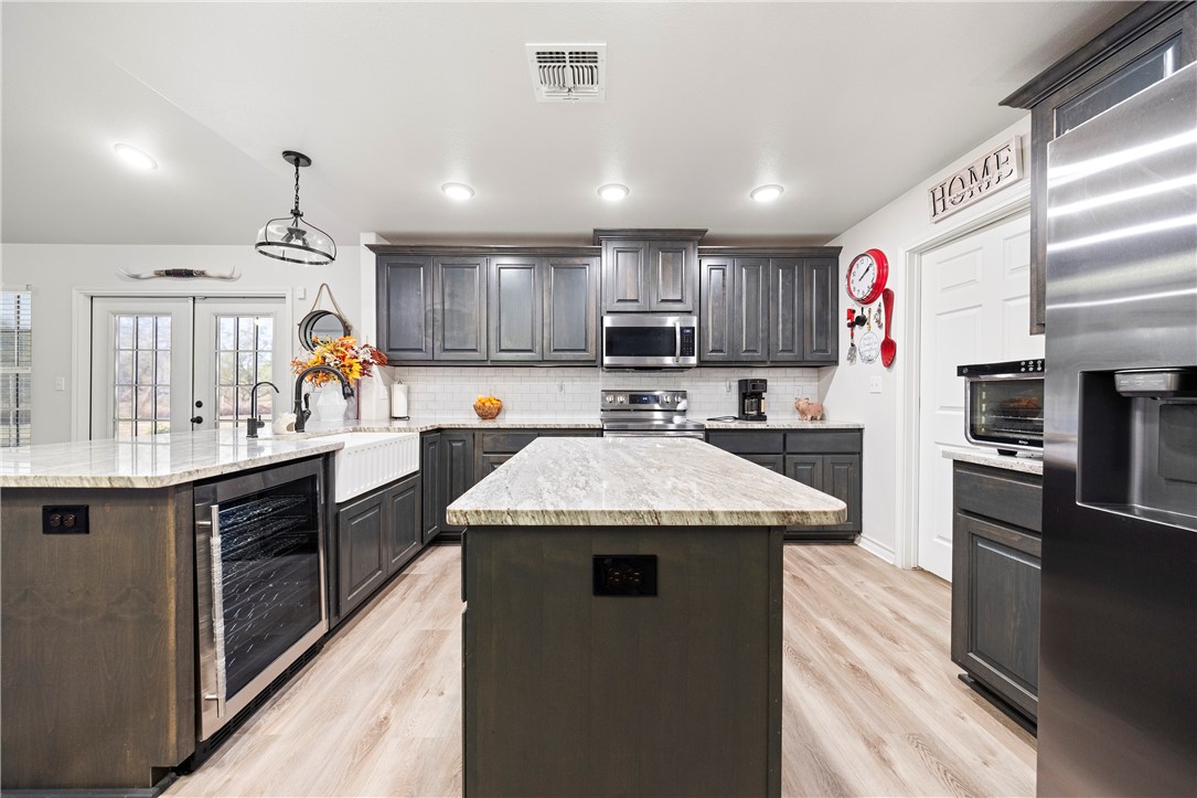 9227 Baker Road Sinton, TX 78387 - Photo 16 of 28 a kitchen with kitchen island granite countertop wooden cabinets a refrigerator and a sink
