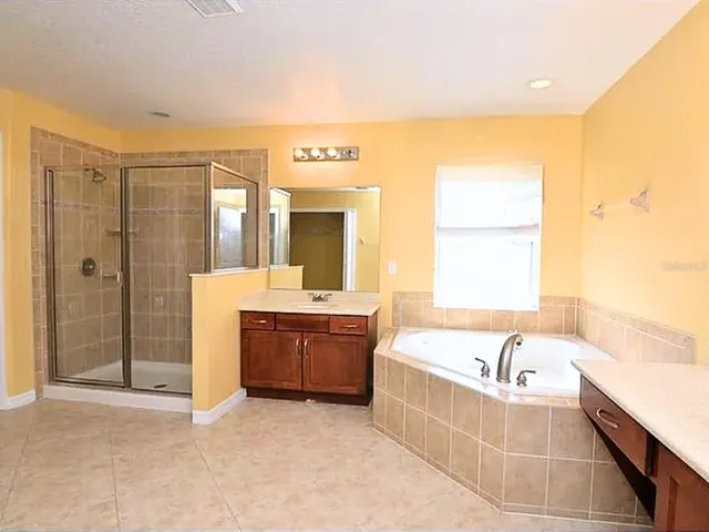 a spacious bathroom with a tub sink and mirror
