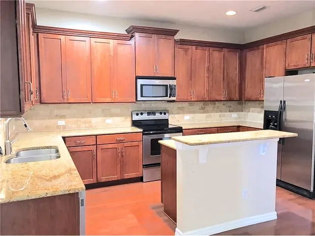 a kitchen with a refrigerator stove top oven sink and cabinets