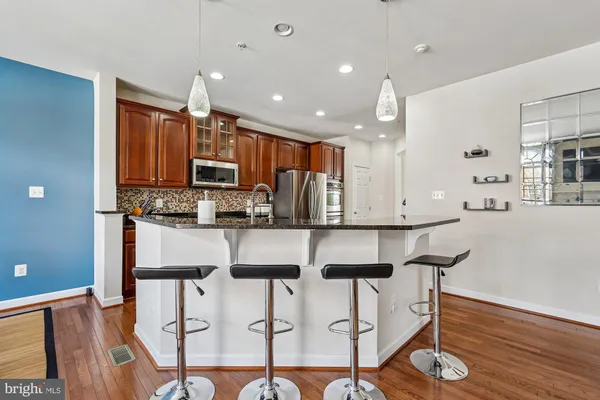 a kitchen with stainless steel appliances kitchen island granite countertop a table chairs refrigerator and microwave