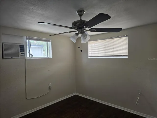 a view of a small space with wooden floor fan and windows
