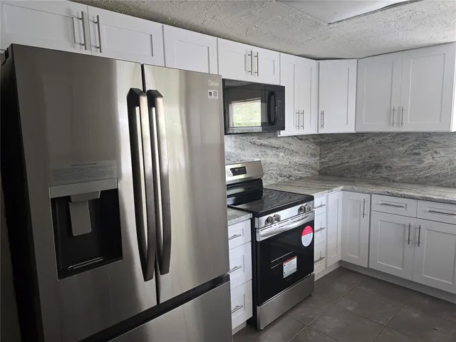 a kitchen with stainless steel appliances granite countertop a refrigerator a stove a sink and a granite counter tops