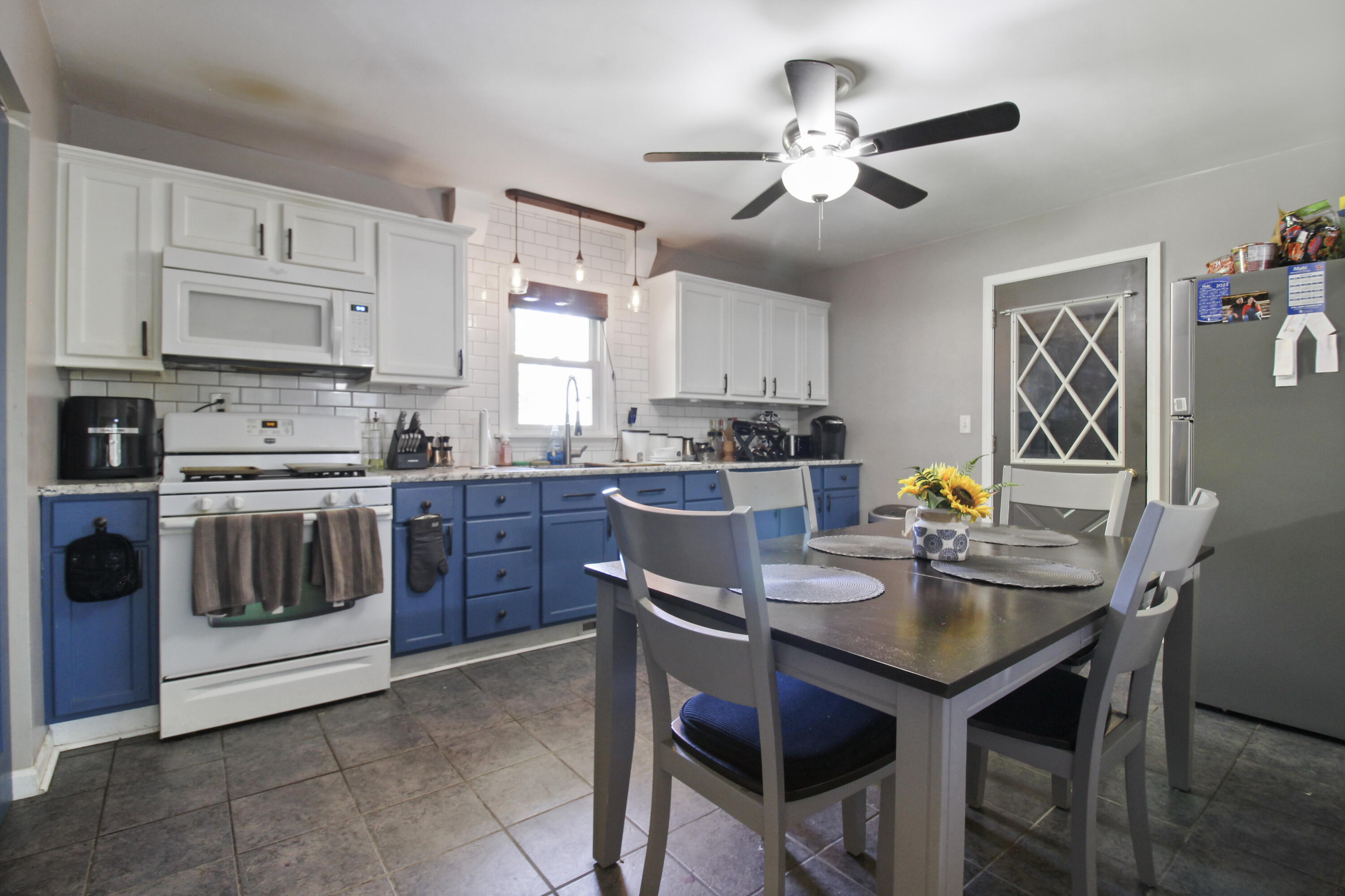 7714 Wallace Street Merrillville, IN 46410 - Photo 6 of 14 a kitchen with a stove a sink a kitchen island with a dining table and chairs