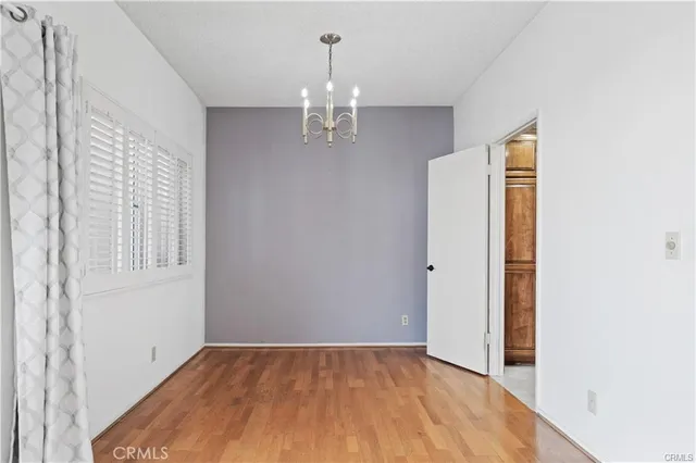 a view of an empty room with chandelier and wooden floor