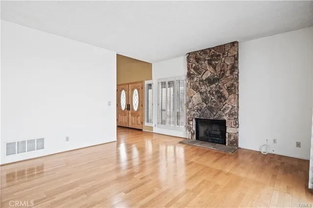 a view of empty room with wooden floor and fireplace