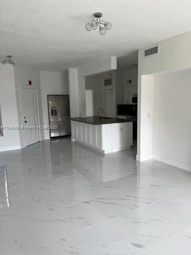 18344 Northwest 68th Avenue, Unit F Hialeah, FL 33015 - Photo 2 of 14 a large white kitchen with kitchen island a sink stainless steel appliances and cabinets