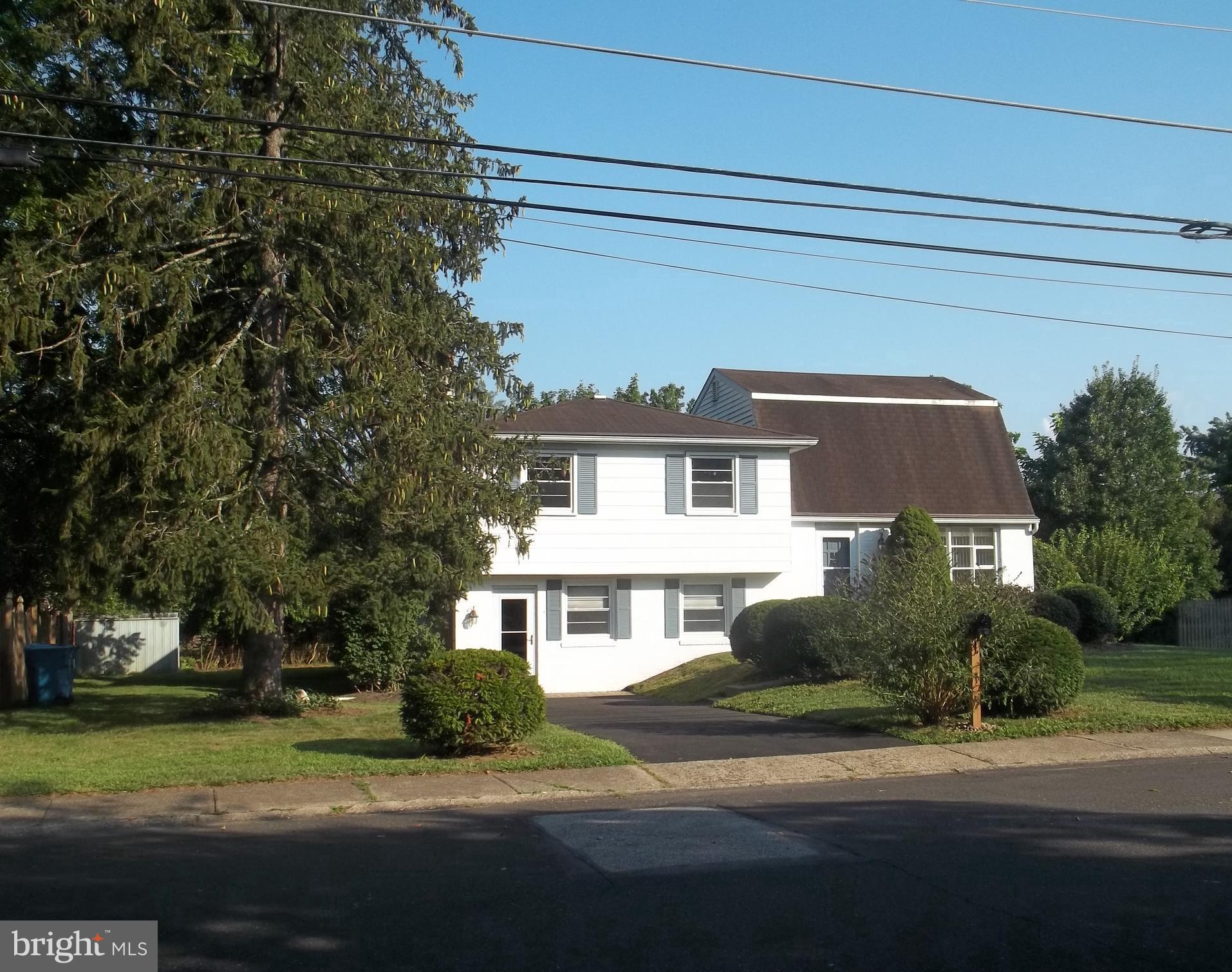 a view of a white house next to a yard with big trees