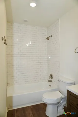 a bathroom with a bathtub shower sink mirror and toilet
