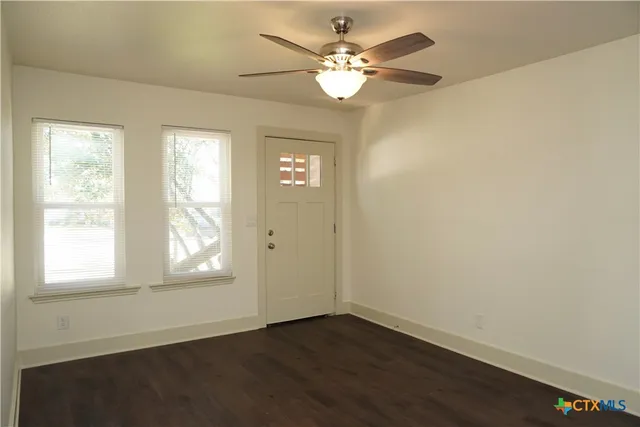a view of an empty room with wooden floor and a window