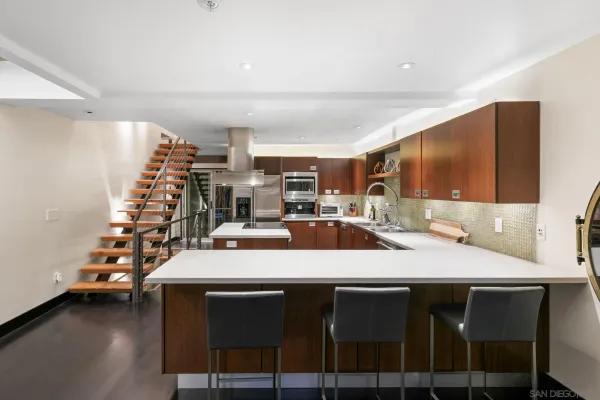 a view of a dining room with furniture one side kitchen view and wooden floor