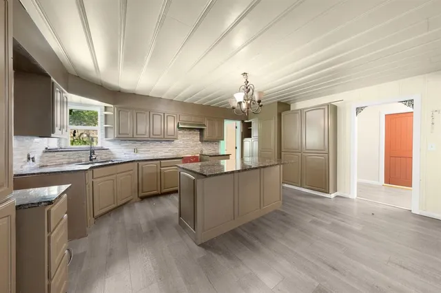 a large kitchen with a center island wooden floor stainless steel appliances and cabinets