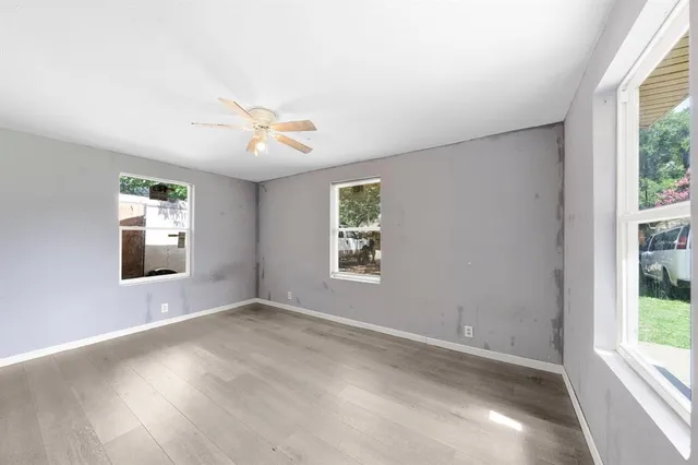 an empty room with a window and a ceiling fan