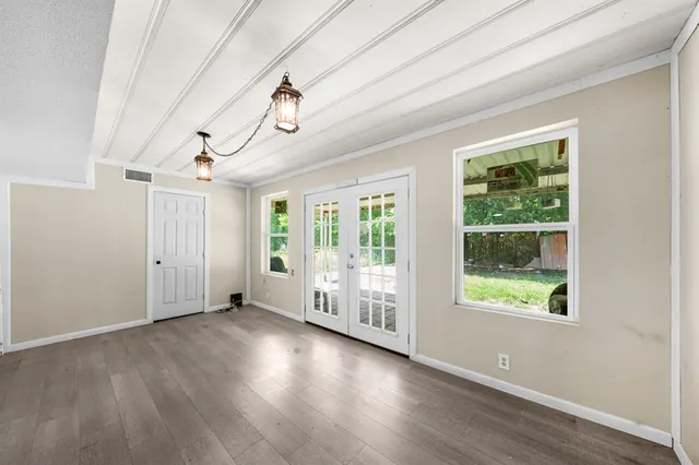 an empty room with wooden floor and windows